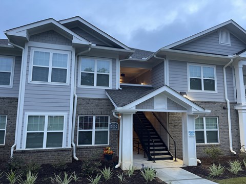A modern two-story house with a front porch and stairs leading to the entrance.