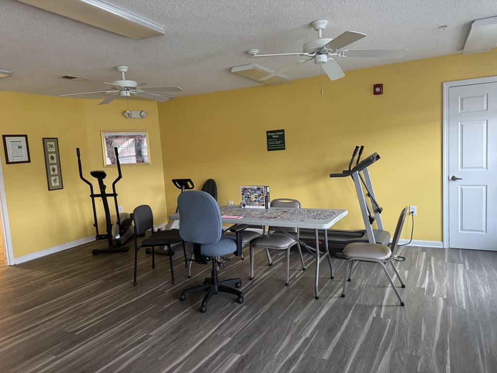 A room with a yellow wall and a white ceiling fan.