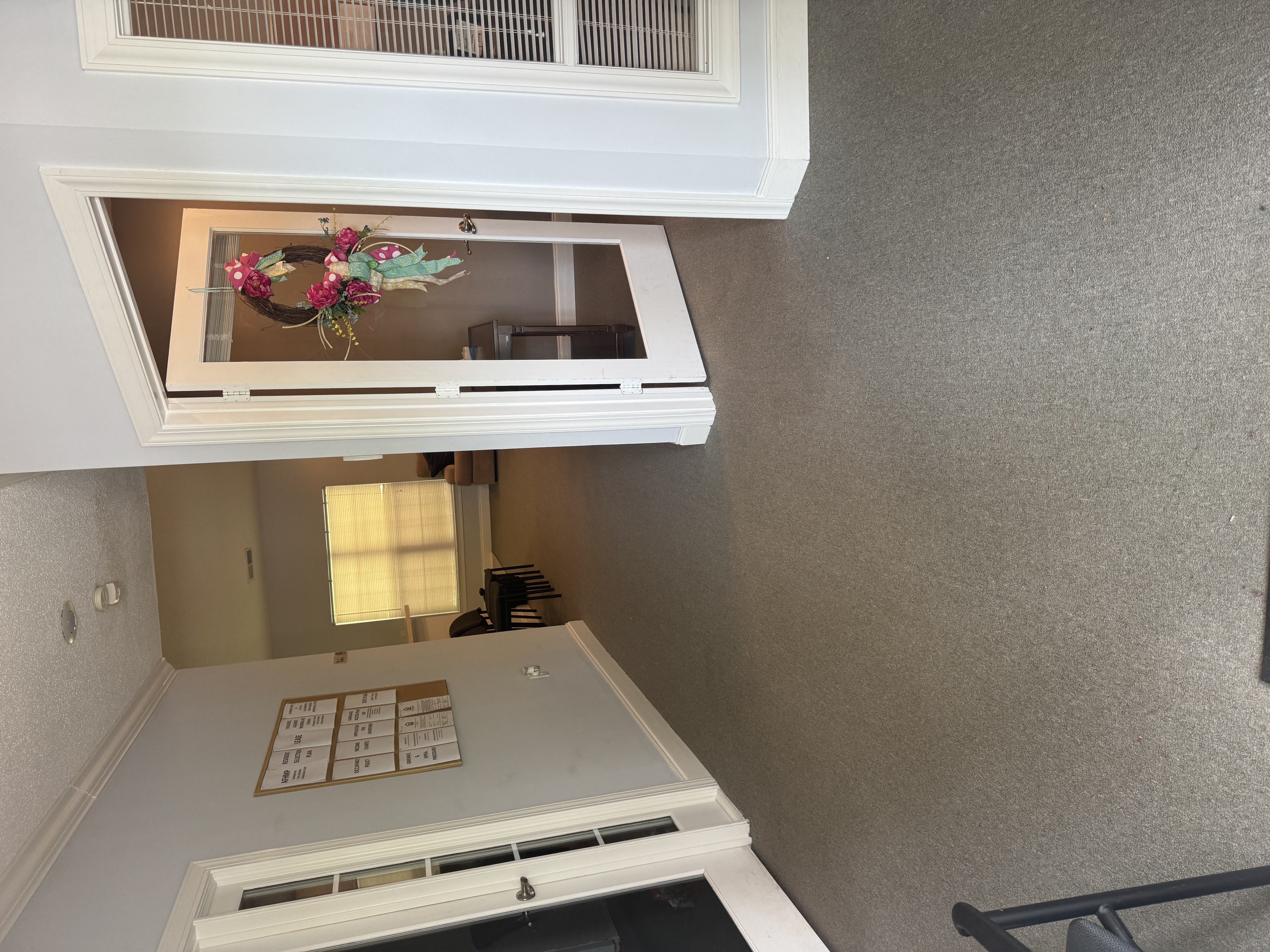 A white kitchen with a wreath on the window.