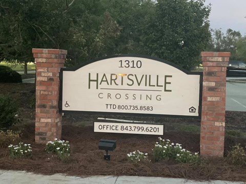 A sign for Hartsville Crossing with a phone number and office number.