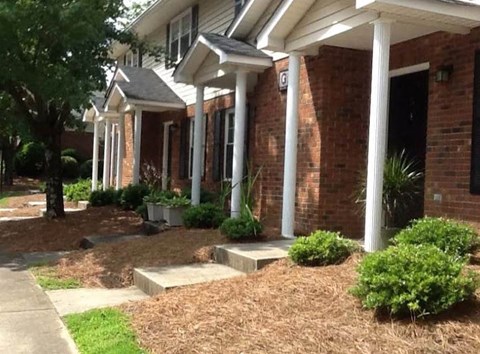 a brick house with white pillars and a sidewalk