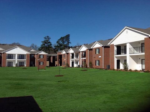 A row of houses with a green lawn in front.