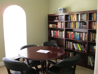 a library with a table and chairs and a bookshelf