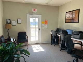 a living room with a desk and chairs and a door