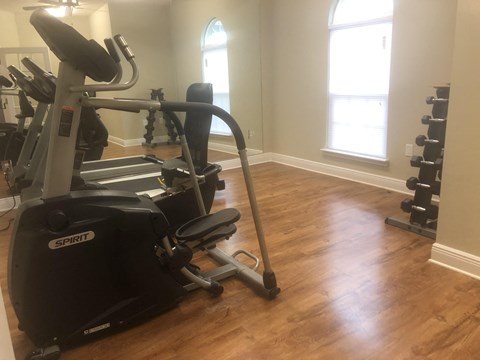 a home gym with exercise equipment in a room with wood floors