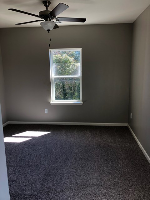 A room with a ceiling fan and a window.