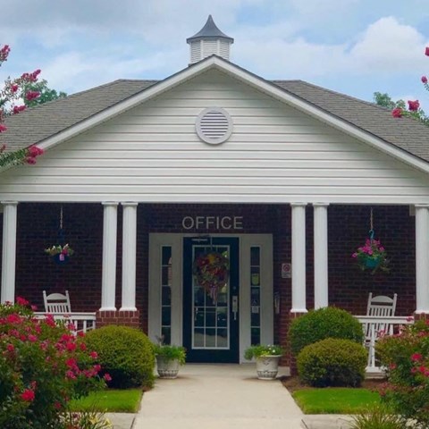 the front of an office building with a sidewalk and chairs