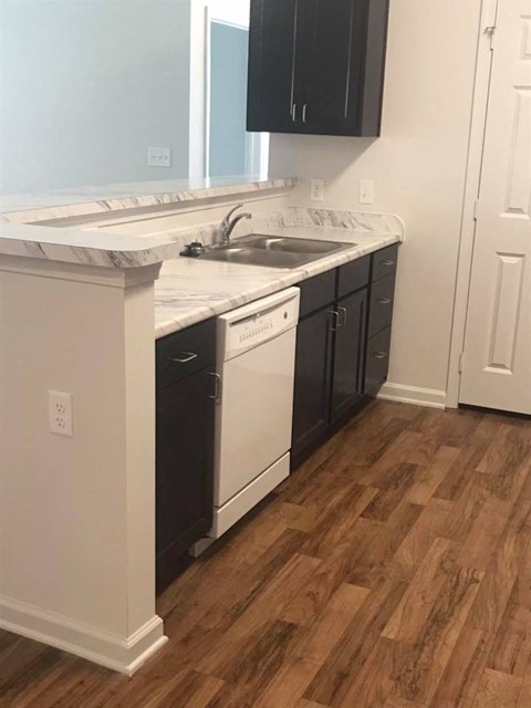 A kitchen with black cabinets and white appliances.