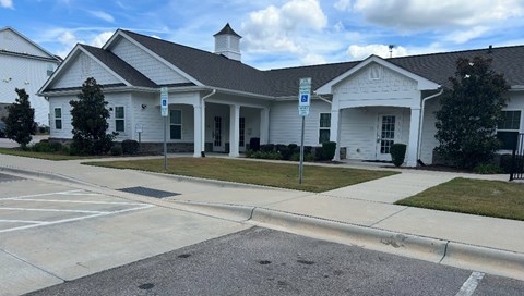 A white building with a black roof and a parking lot in front.