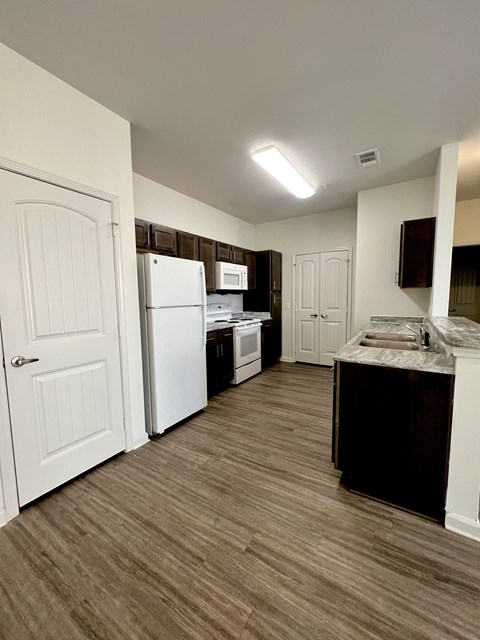 an empty kitchen with white appliances and wood flooring in an apartment
