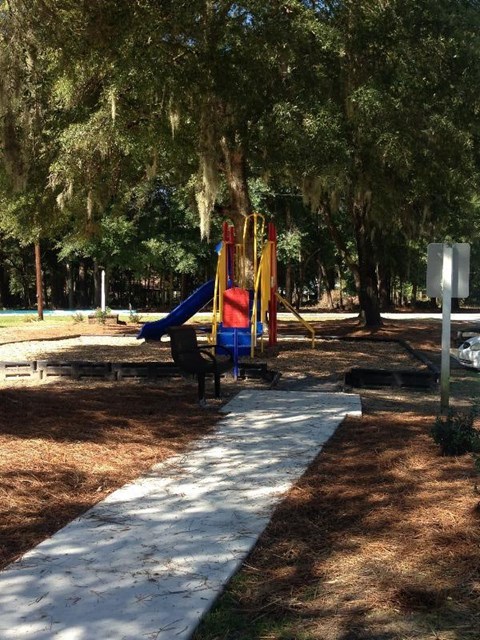 A playground with a slide and a white pathway.