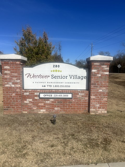 A sign for Westover Senior Village stands in front of a grassy area.