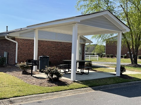 a pavilion with a picnic table in front of a brick building