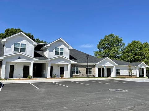 A row of white houses with a parking lot in front.