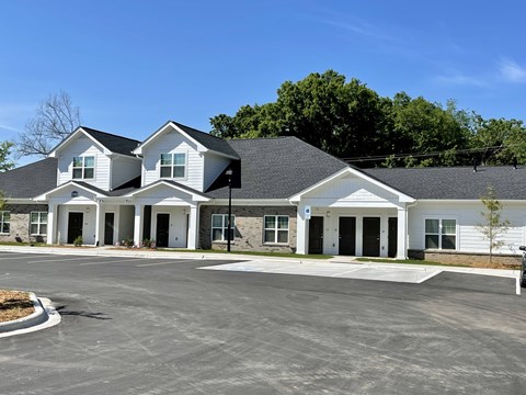 A large white building with a black roof and a parking lot in front.