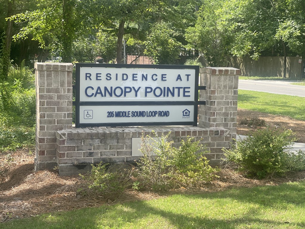 A sign for Residence at Canopy Pointe is shown in front of a green lawn.