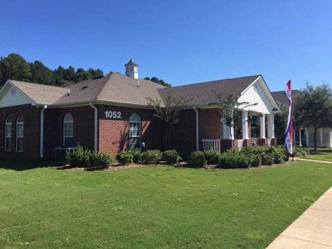 a red brick house with a lawn and a flag