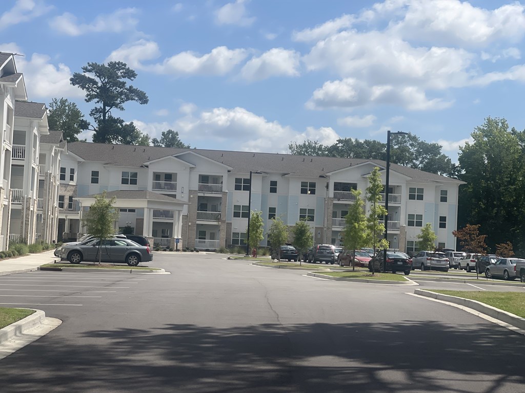 A parking lot in front of a white apartment building.