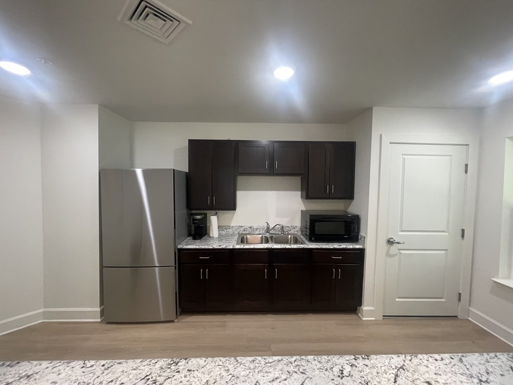 A kitchen with a refrigerator, microwave, and sink.