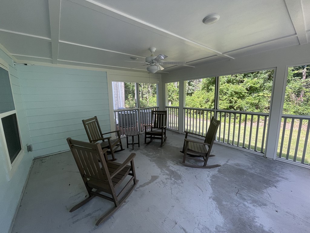 A sunroom with a white ceiling and wooden rocking chairs.