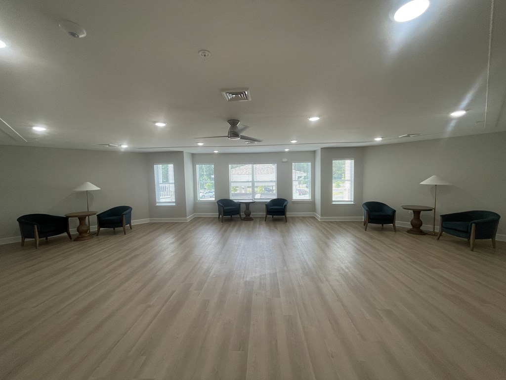 A spacious room with wooden floors and multiple seating options.