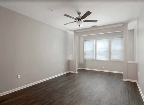 A room with a ceiling fan and a window with blinds.