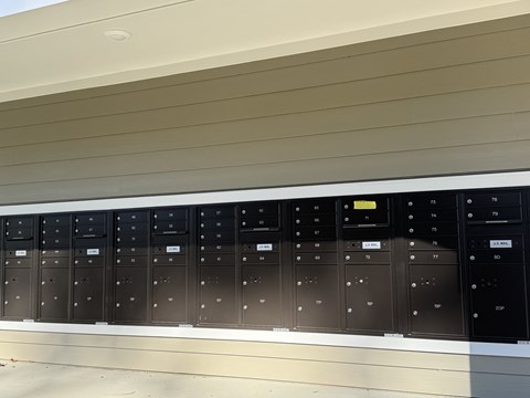 A row of black electrical switchboards are mounted on a wall.