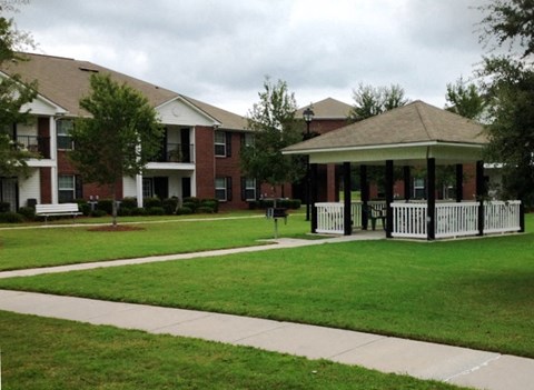 a gazebo in the grass in front of an apartment building