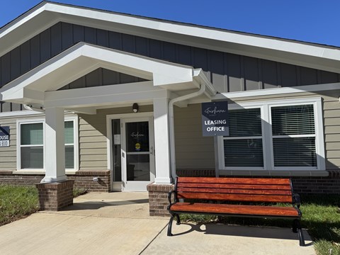 A bench is in front of a leasing office.