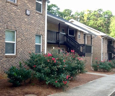 an apartment building with flowering bushes in front of it