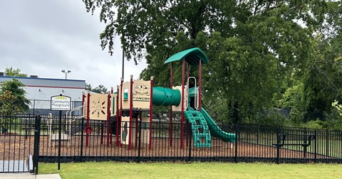 A playground with a green slide and a red and white structure.