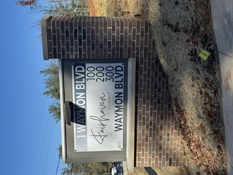 A sign for 1 Waymon Blvd is displayed in front of a brick pillar.