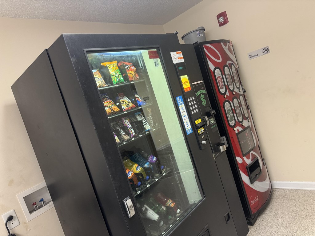 A black vending machine with a red and white one next to it.
