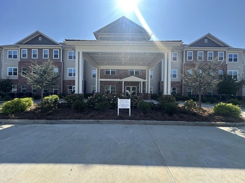 A sunny day at a large, multi-story residential building with a driveway in front.