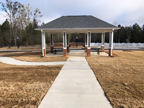 A gazebo with a walkway leading to it is surrounded by a grassy area.