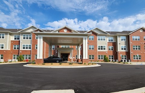 A black car is parked in front of a building with a covered entrance.