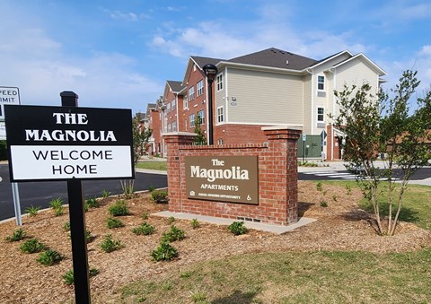 The Magnolia Apartments sign in front of a building.