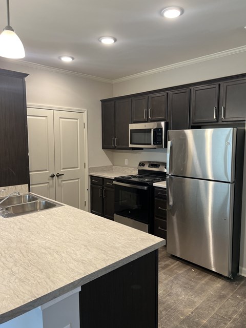 A kitchen with a stainless steel refrigerator and a white counter top.