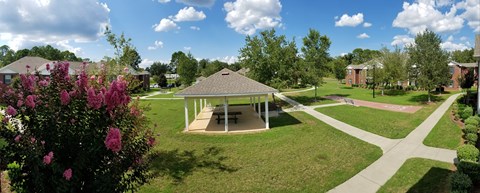 A gazebo is surrounded by a green lawn and a pathway.