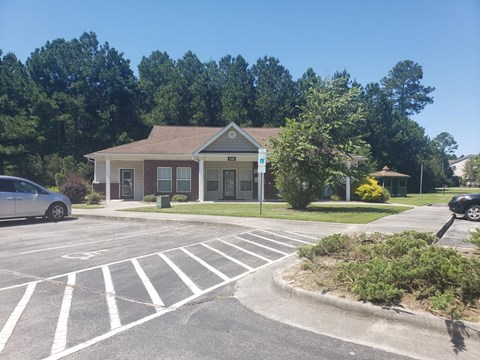 A small building with a parking lot in front of it.