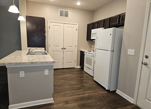 A kitchen with a white refrigerator and cabinets.