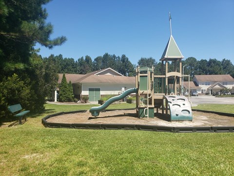 A playground with a green slide and a wooden structure.