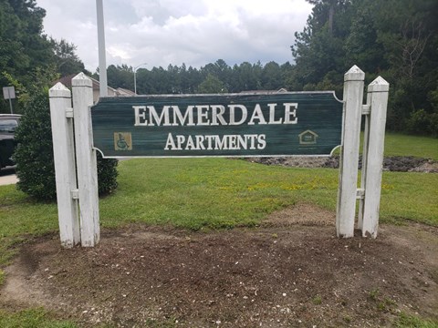 A sign for Emmerdale Apartments is displayed in front of a grassy area.