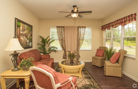 A living room with a yellow coffee table and red chairs.