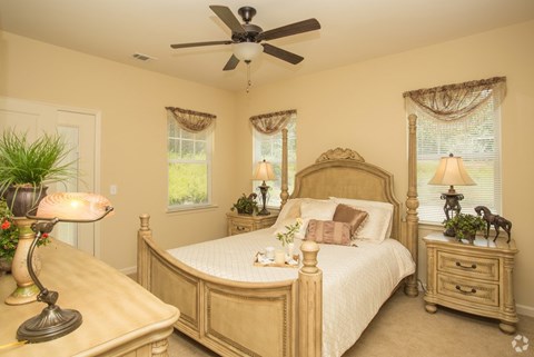 A bedroom with a large bed, a dresser, and a ceiling fan.