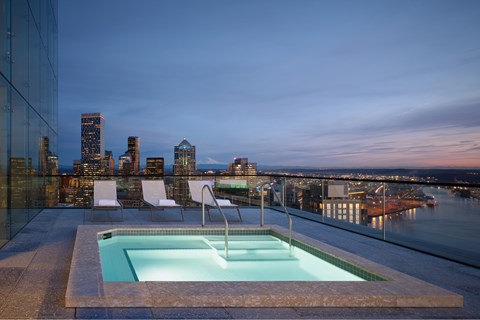 A small pool on a balcony overlooking a city skyline at dusk.