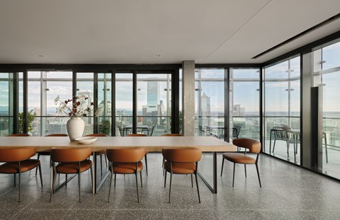 A conference room with a long table and chairs with a view of the city outside the windows.