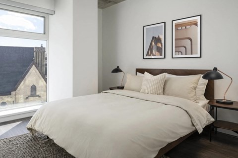 A bedroom with a large bed and two pictures on the wall.