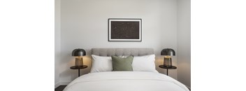A bed with white sheets and two black lamps on either side.
