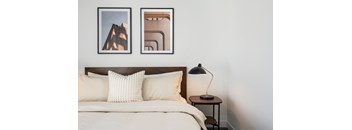 A bed with a white comforter and two pillows sits under a picture of a building.